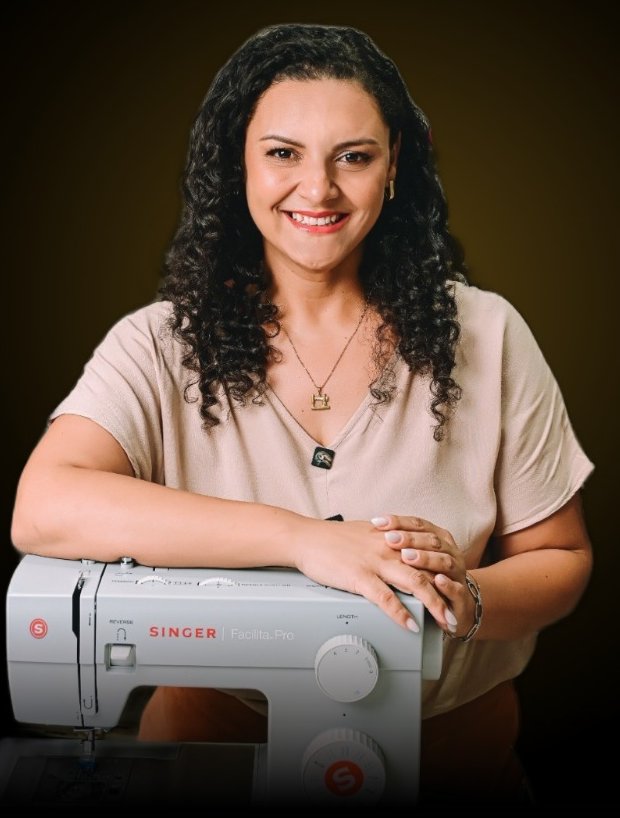 Carine Martins apoiada na máquina de costura